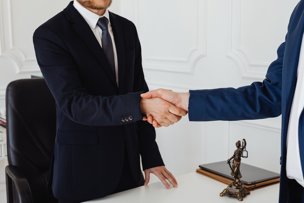 Epresários apertando as mãos após reunião sobre marketing jurídico